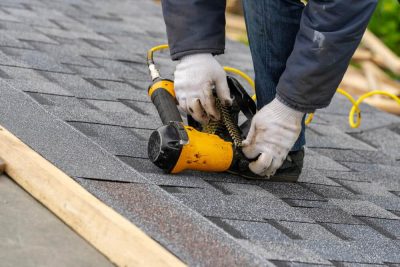 expert putting asphalt shingle roofing with nail gun