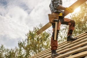 Building Construction Site Roof Worker with a Plank in His Hands. Construction Industry Theme.