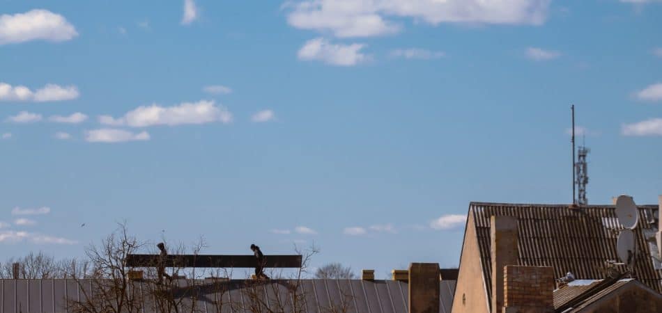 Roofing professional using an infrared thermal imaging camera to find a hidden roof leak