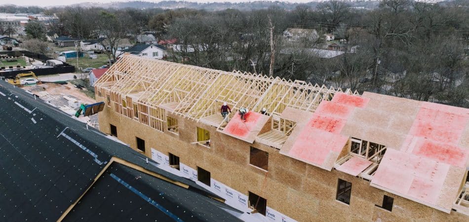 Roofing contractor installing new plywood roof decking during a tear-off