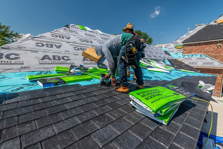 Contractor inspecting slate roof flashing on a commercial rooftop