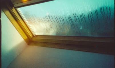 Underside of a roof deck showing condensation and moisture staining in an attic